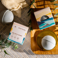 CBD bath bomb packaging with a bath bomb on a wooden tray in a bathroom setting.